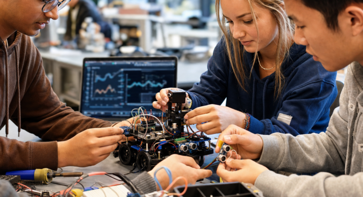 Students and makers assembling a physical AI robot prototype with sensors and edge hardware Students and makers assembling a physical AI robot prototype with sensors and edge hardware