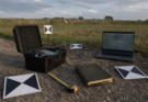 Outdoor field documentation setup with a small drone case, ground control targets, measuring tape, and laptop