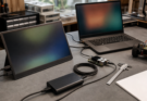 Portable monitor on a workshop bench showing engineering dashboards beside cables and field test gear
