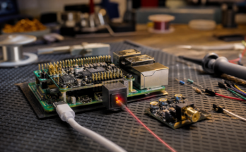 Raspberry Pi-style audio prototype board with an optical TOSLINK cable on a warm maker bench
