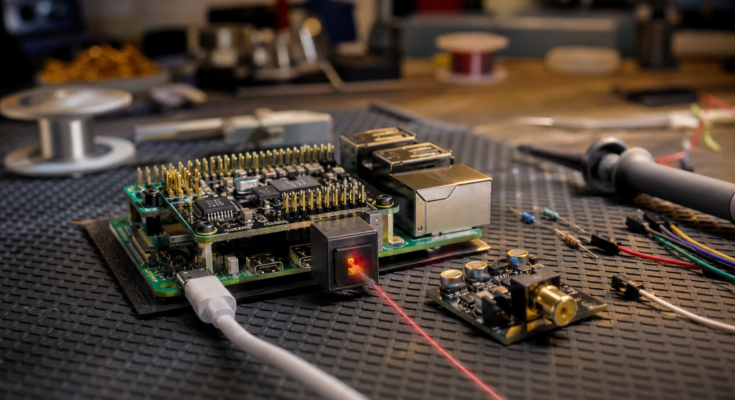 Raspberry Pi-style audio prototype board with an optical TOSLINK cable on a warm maker bench Raspberry Pi-style audio prototype board with an optical TOSLINK cable on a warm maker bench