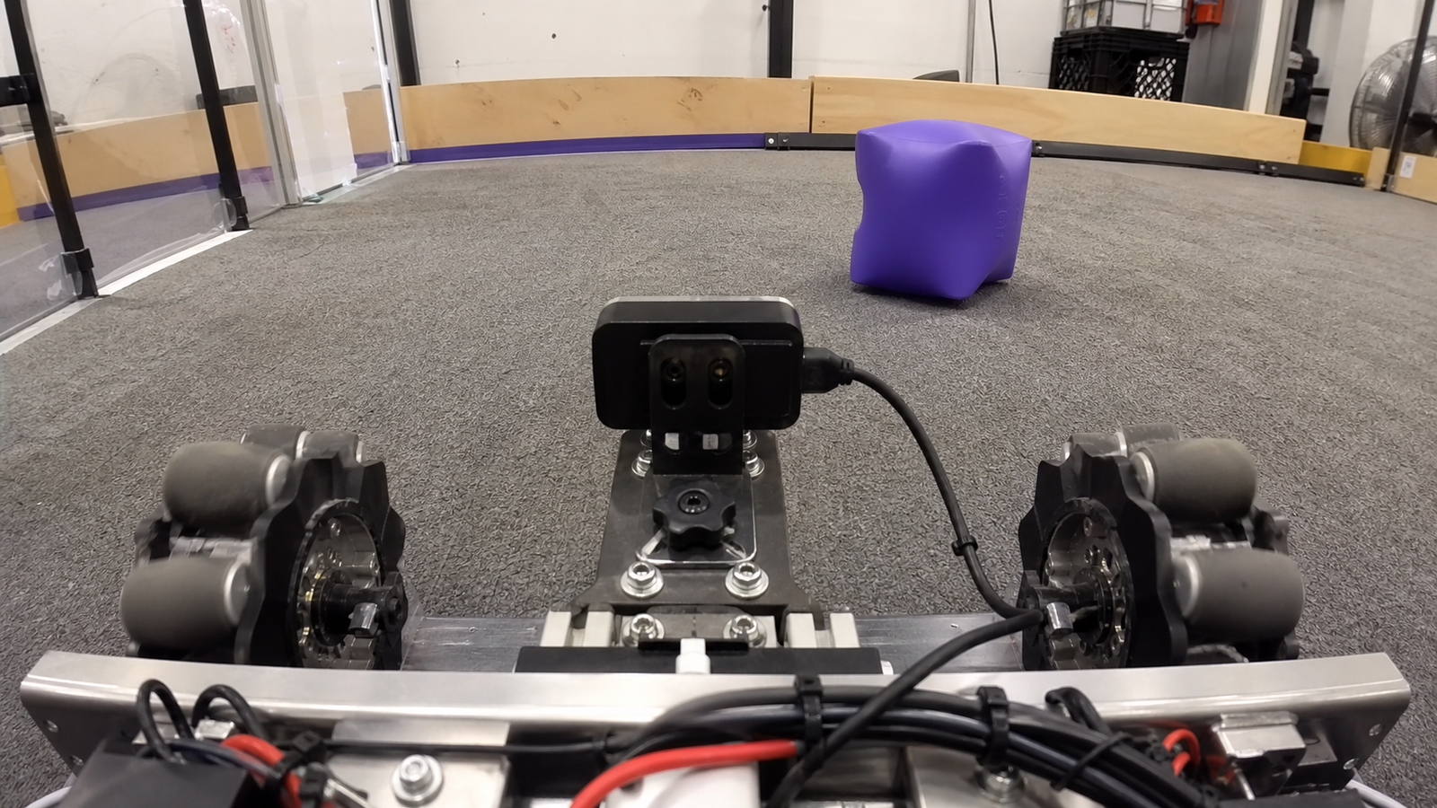 Action camera mounted low on a robotics test cart aimed at wheels and a field marker