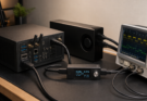 Editorial photo of a compact AI workstation test bench with a small form factor PC, external accelerator enclosure, power met