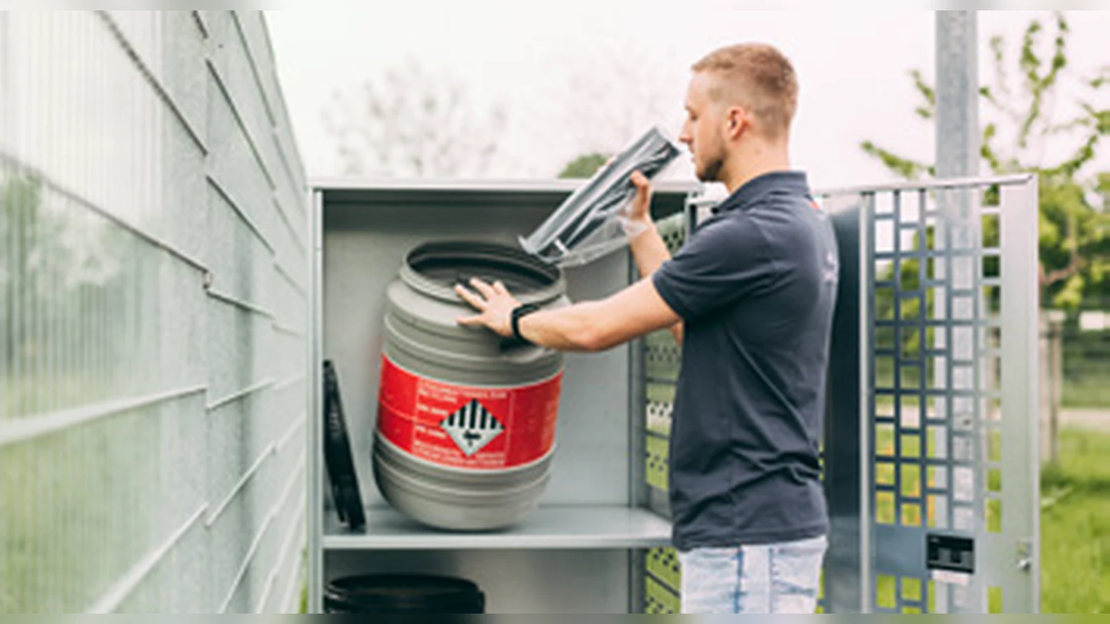 Worker placing a battery safety container in a separate outdoor cabinet