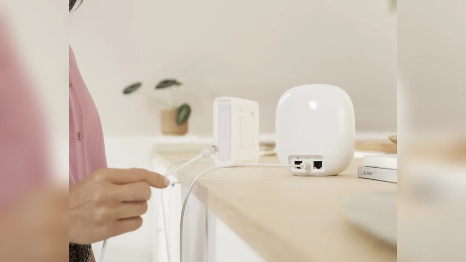 Person handling a network cable beside a Nest Wifi Pro router