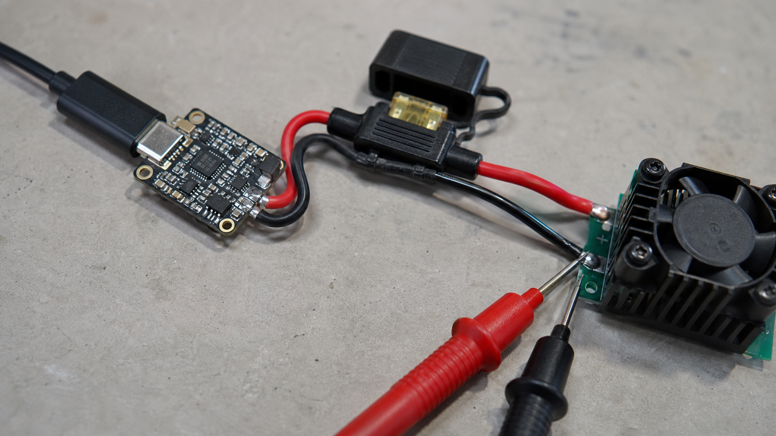 USB-C PD trigger board connected to a small load and multimeter on an electronics bench