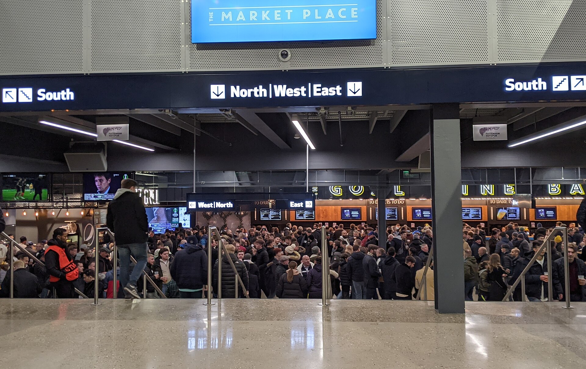 Crowded concourse inside Tottenham Hotspur Stadium.
