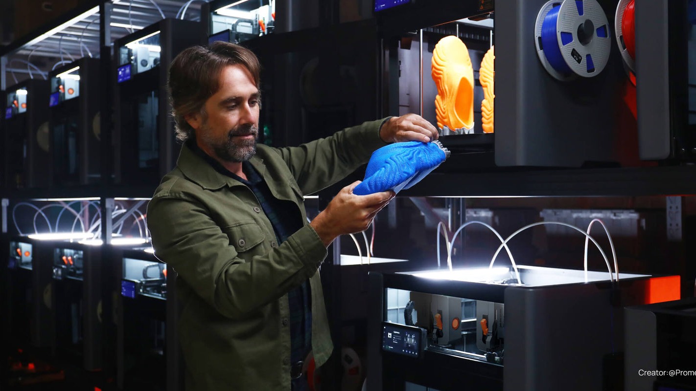 Operator holding a blue print in a room of LightMake 3D printers.