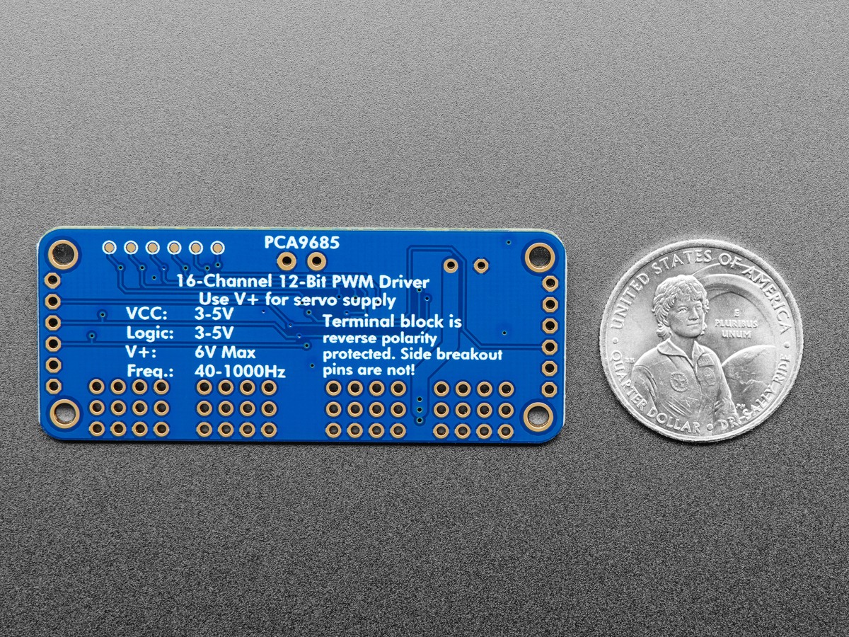 Back of an Adafruit PCA9685 servo driver board beside a coin