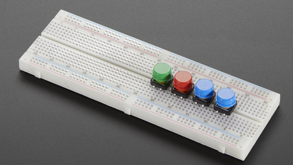 Four tactile pushbuttons installed on a solderless breadboard
