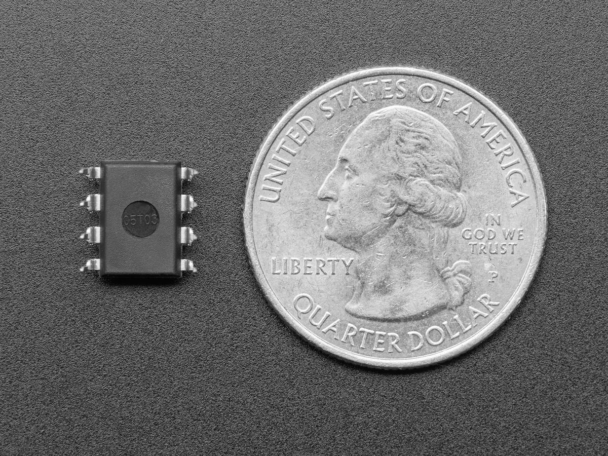 TLC551 timer IC beside a US quarter for scale