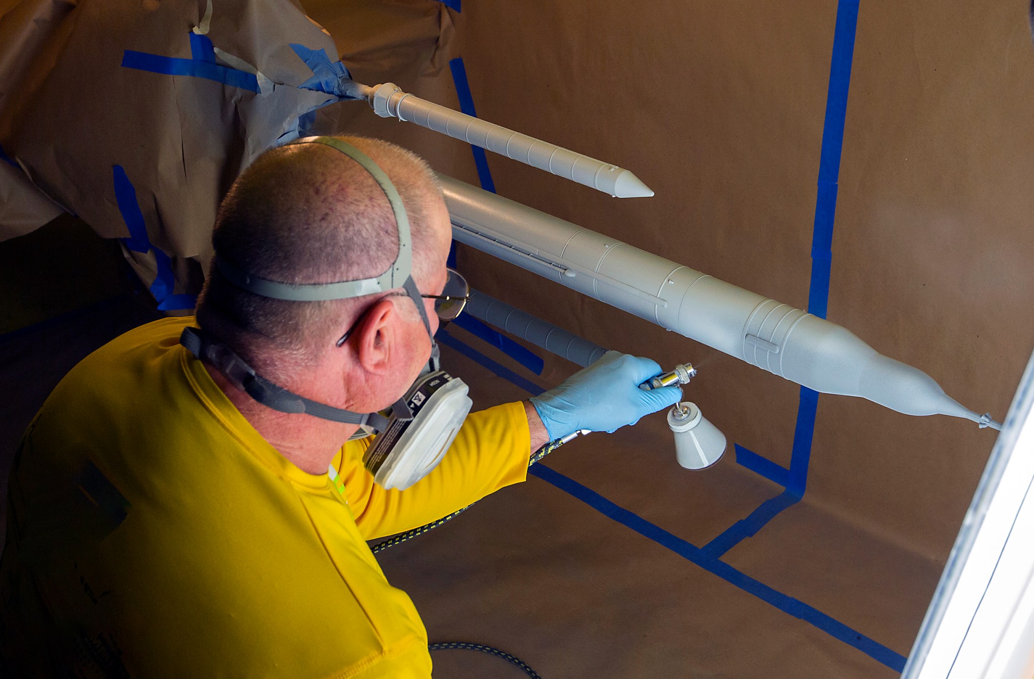NASA technician spraying pressure-sensitive paint onto a scale rocket model