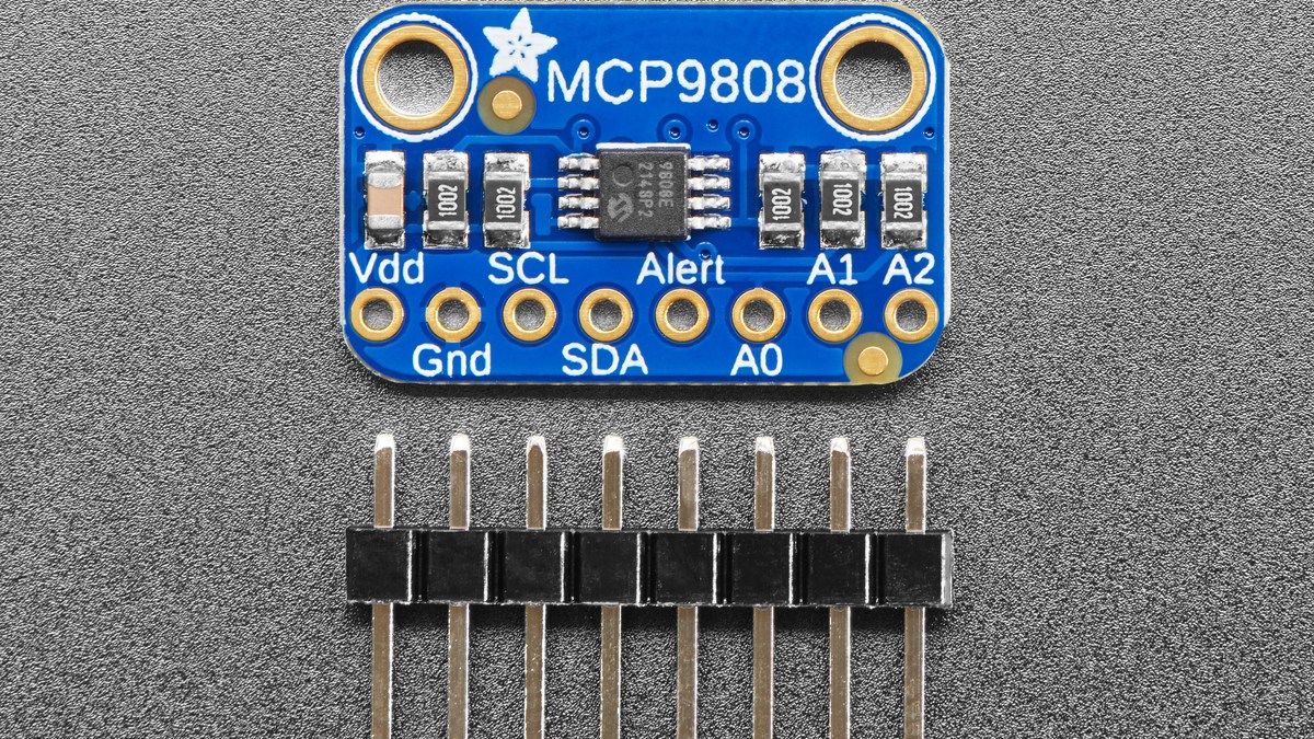 Front view of the MCP9808 breakout beside its loose header pins